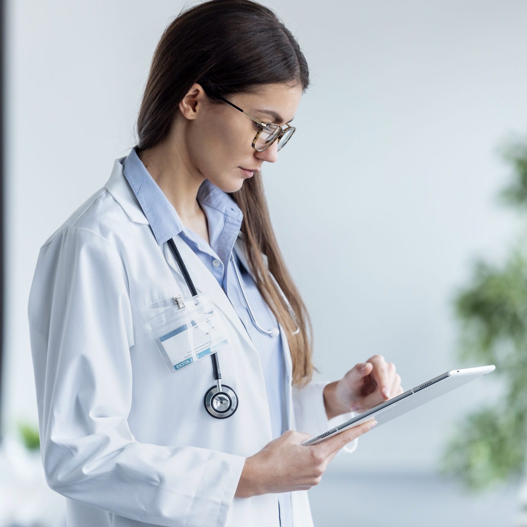 Shot of female doctor using her digital tablet while standing in the consultation.